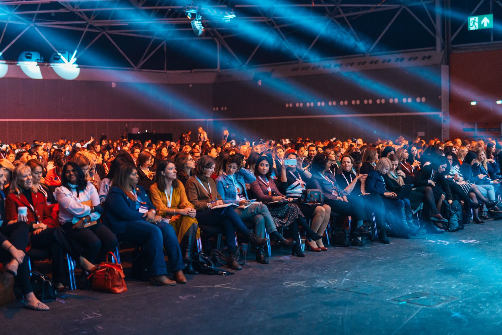 A large audience seated at a conference under stage lighting